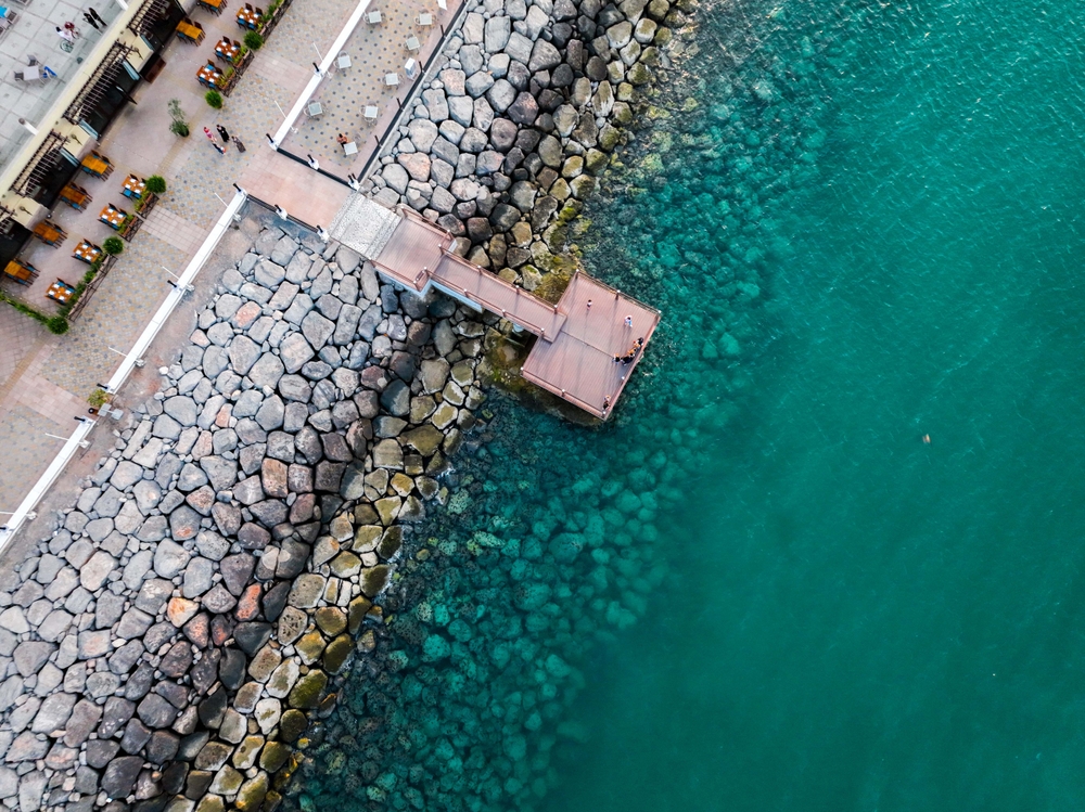 Pristine Waters - Al Marjan Island Coastline Crystal clear turquoise Arabian Gulf waters meeting stone breakwater pier at Al Marjan Island pristine coastline in Ras Al Khaimah
