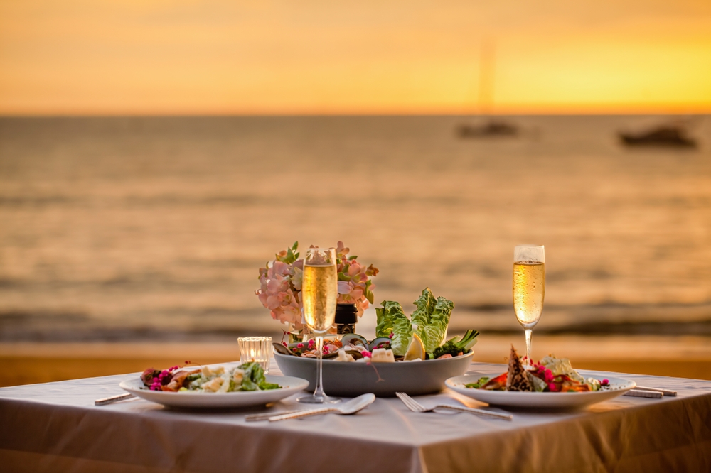 Sunset Dining - Al Marjan Island Restaurants Beachfront dining experience at sunset with tables on white sand, turquoise waters, and golden sky at Al Marjan Island waterfront restaurants